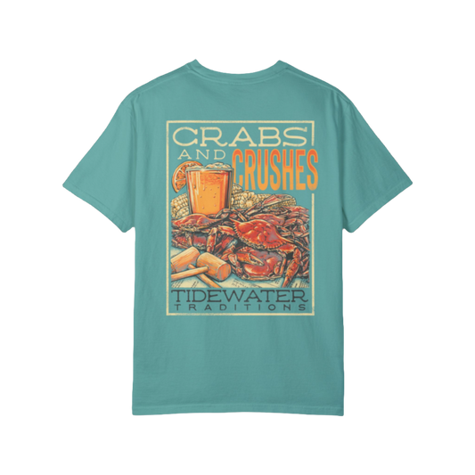 A Tidewater Traditions t-shirt featuring a colorful design with the text 'Crabs and Crushes.' The graphic depicts a Maryland blue crab feast with a glass of orange crush, a popular local drink, along with crab mallets and corn on the cob.